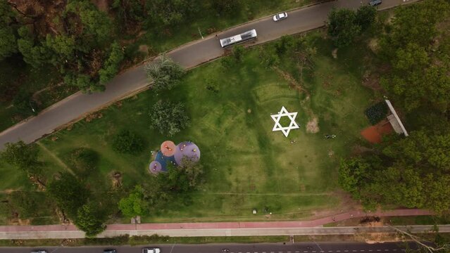 Panorama over the park, the memorial star of David and the park with trees fallen after the storm, a highway with traffic, a view from above