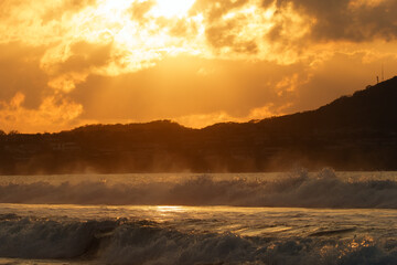 Obraz premium Beautiful orange sunset in the tropical beach with cottages and waves.