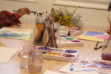 Children paint, paint, brushes and paper holding the children's hands.