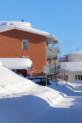 Brick house in a residential area in &Ouml;stersund. Winter with a lot of snow after snowfall on footpaths and in the parking lot. Pine trees near houses with snow on the twigs.
