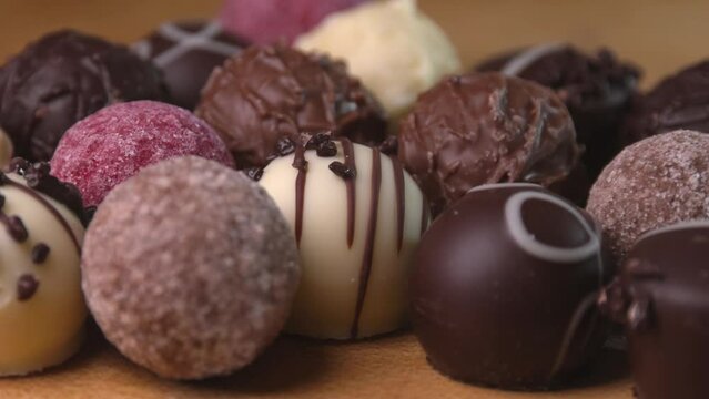 Chocolate truffles on wooden surface with smooth panning motion. Close up of assorted pralines