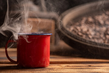 Coffee, red coffee mug on rustic wood and accessories, dark background, selective focus.
