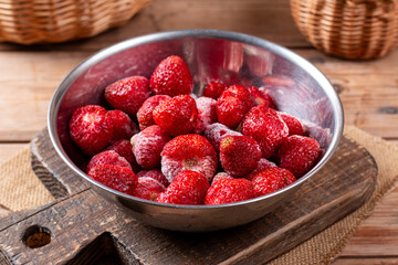 Frozen strawberries in a bowl on a table. Frozen food