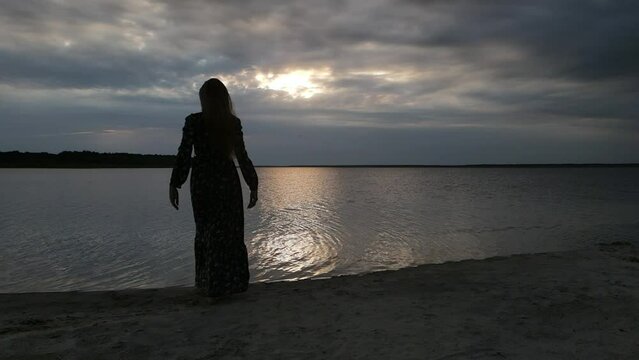 Lake or sea at sunset, young woman walking on the beach and on the water
