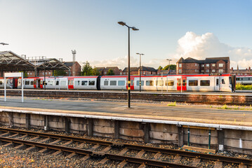 View of a train station with a diesel commuter train stationary at a deserted platform at sunset