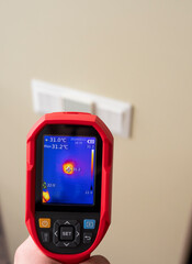 An electrician checks the heating of household outlets and light switches. Overheating of the...