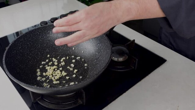 Close up of Chef cook hands cooking and toss roasted onion and garlic in frying wok pan on gas stove. Flying food levitation. 