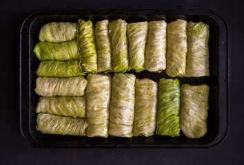 Stuffed cabbage rolls in a baking tray on a black background. Selective focus. Toned. Ukrainian...