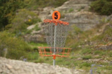 Disc golf (frolf) basket on a forest course in summer with a shallow depth of field