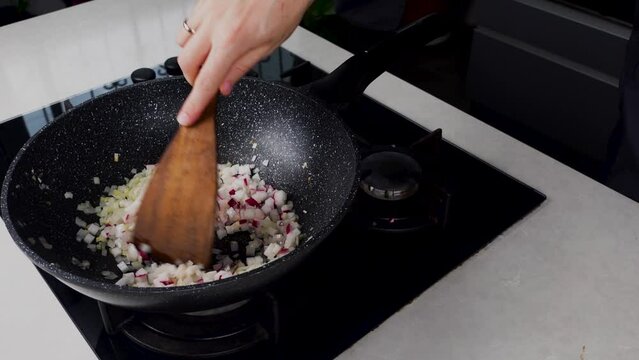 Close up of Chef cook hands cooking and toss roasted onion and garlic in frying wok pan on gas stove. Flying food levitation. 