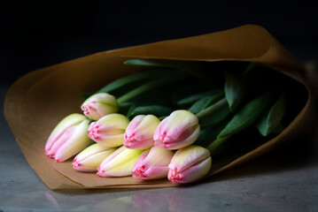 Beautiful buoquet of pink and yellow tulips on a table with brown craft paper 
