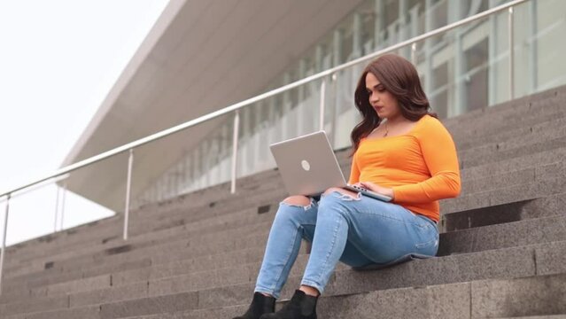 Trans gender student working in laptop in campus outdoors