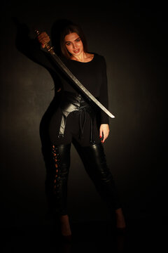 Woman in black with vintage katana sword low key portrait
