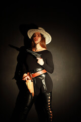 Fototapeta premium Beautiful young woman in white hat with two old revolvers low key portrait