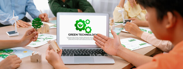 Green technology logo displayed on green business laptop while business team presenting green...