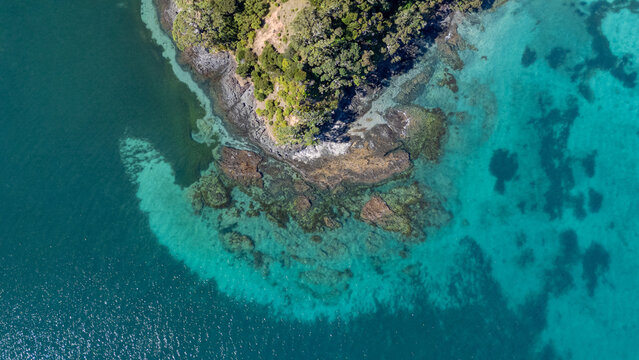 Aerial view of an island surrounded by crystal blue water and rocks
