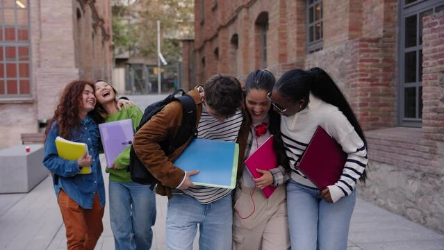 Multiracial group of cheerful erasmus students enjoying. Young friends walking together outdoors university campus and looking at each other smiling. Generation z colleagues and youth relationships
