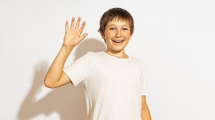 The teenager shows an open palm to the camera and smiles friendly. The concept of greeting.