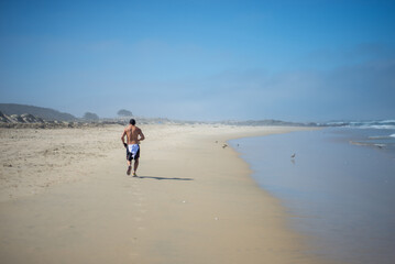 a man running on the send during a sunny day