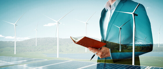 Double exposure graphic of business people working over wind turbine farm and green renewable...