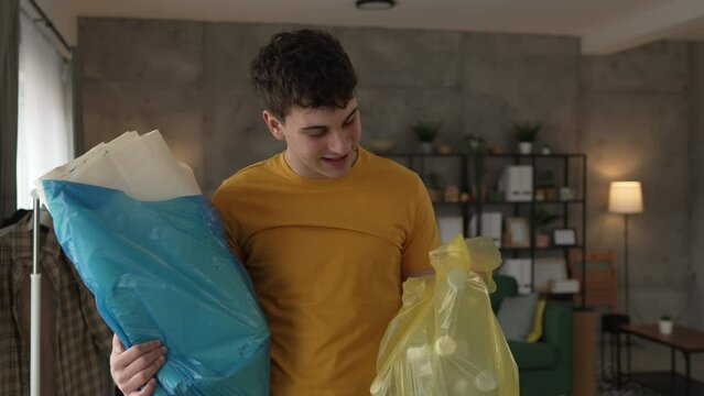 young man recycle at home sorting waste plastic paper and glass
