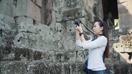 An enthusiastic travel photographer stands among ancient ruins, looking up and capturing the essence of historical exploration.
