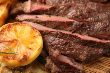 Delicious grilled beef with lemon on table, closeup