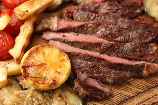 Delicious grilled beef with vegetables and lemon on table, closeup