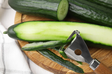 Fresh cucumbers and peeler on table, closeup