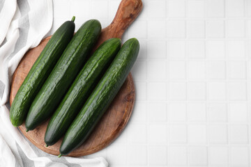 Fresh cucumbers on white tiled table, top view. Space for text