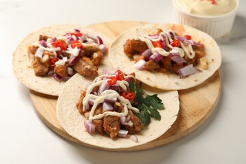 Delicious tacos with vegetables, meat and sauce on white table