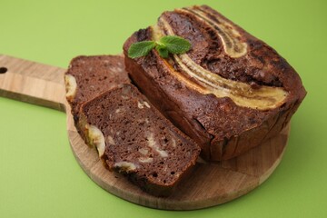 Delicious banana bread with mint on green background, closeup