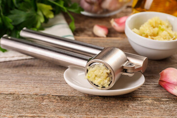 Garlic press with mince on wooden table, closeup