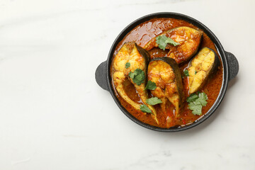 Tasty fish curry on white marble table, top view. Space for text. Indian cuisine