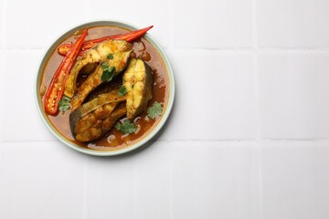 Tasty fish curry on white tiled table, top view. Space for text. Indian cuisine