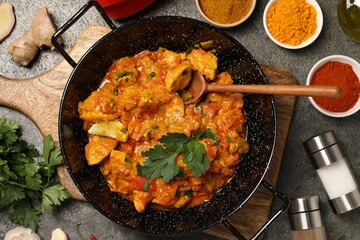 Delicious chicken curry and ingredients on grey table, flat lay