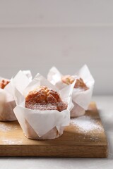 Delicious muffins with powdered sugar on light table