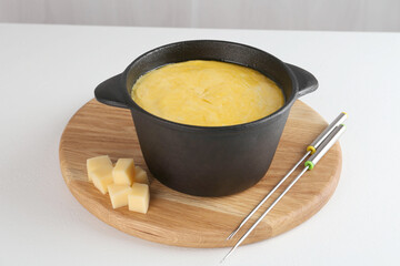 Fondue with tasty melted cheese and forks on white table