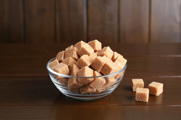 Brown sugar cubes in glass bowl on wooden table