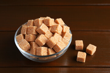 Brown sugar cubes in glass bowl on wooden table