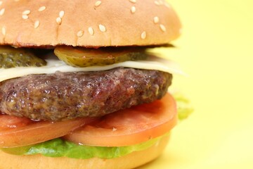 Burger with delicious patty on yellow background, closeup