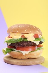 Burger with delicious patty on color background
