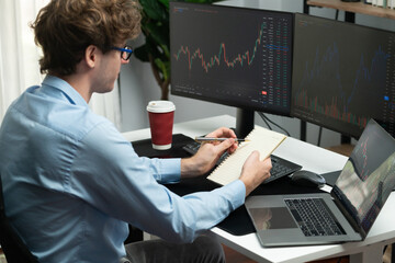 Working young professional business trader concentrating on market stock graph investing in real time screens at home office, analyzing with writing important valued exchange rate concept. Gusher. - obrazy, fototapety, plakaty