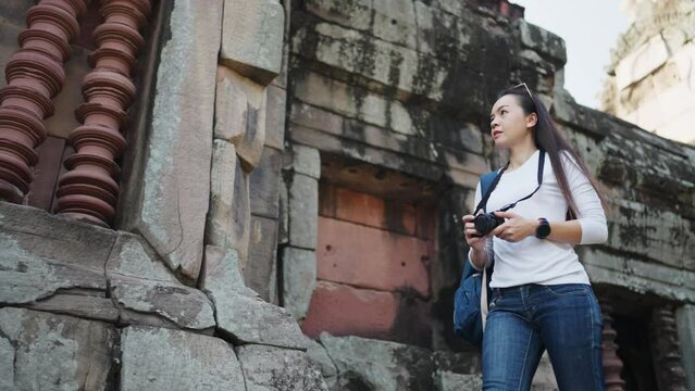 A focused female photographer taking pictures of historic ruins, exploring culture and history through her lens.
