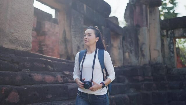 A focused female photographer taking pictures of historic ruins, exploring culture and history through her lens.
