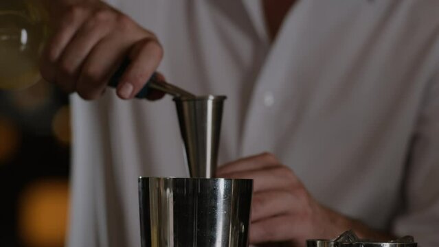 Bartender measures liquor in a jigger for a cocktail