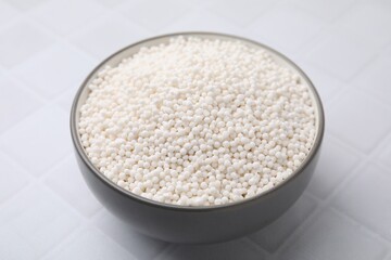 Tapioca pearls in bowl on white tiled table, closeup