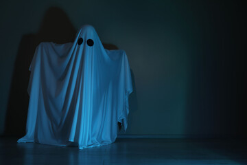 Creepy ghost. Woman covered with sheet in color light, space for text