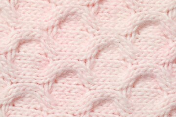 Texture of soft pink knitted fabric as background, top view
