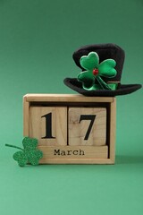 St. Patrick's day - 17th of March. Block calendar, leprechaun hat and decorative clover leaf on green background